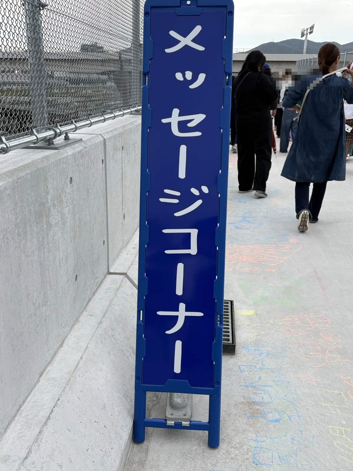 青い看板に「メッセージコーナー」の文字。足もとの床にはチョークの落書きが広がる