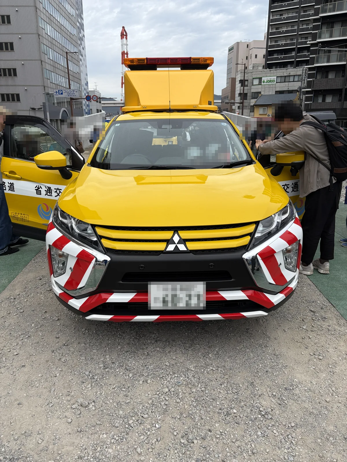 黄色い道路パトロールカー。屋根に表示板と回転灯を載せ、ドアが開いている