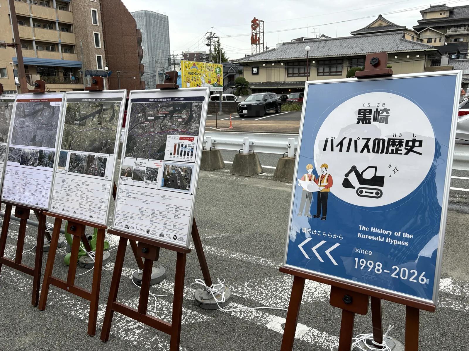 「黒崎バイパスの歴史 since 1998-2026」の看板と、年代ごとの航空写真を並べたパネル