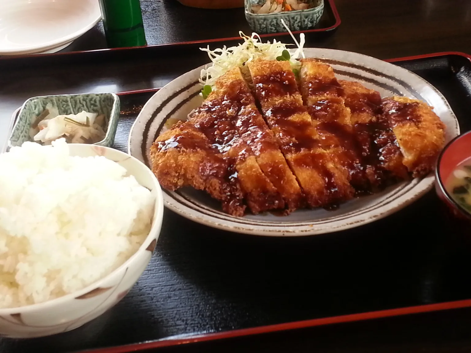 チキンカツ定食。ソースのかかった大きなチキンカツとキャベツ、山盛りのごはん、小鉢